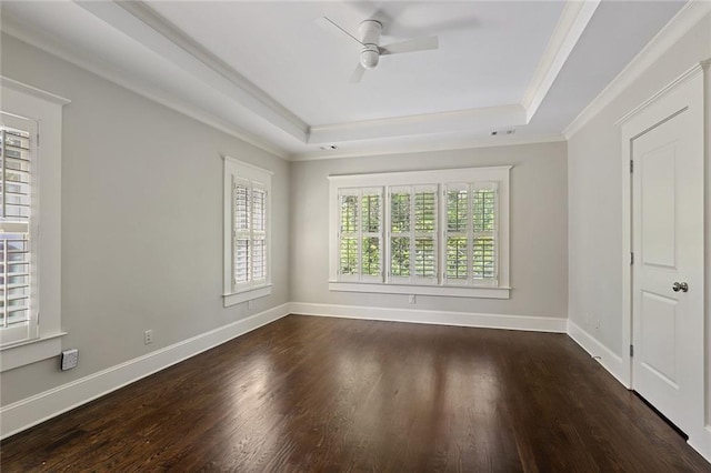 unfurnished room with a tray ceiling, dark wood-type flooring, ceiling fan, and crown molding