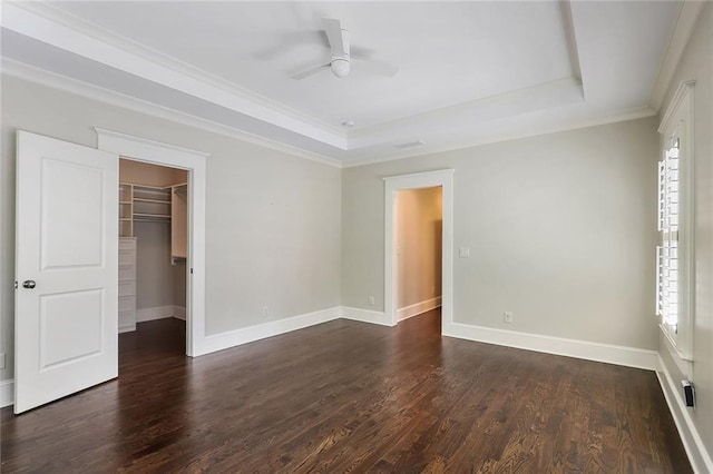 empty room featuring ceiling fan, crown molding, dark hardwood / wood-style floors, and a raised ceiling