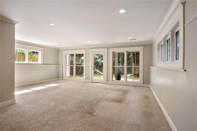 unfurnished room featuring crown molding, a wealth of natural light, and light carpet