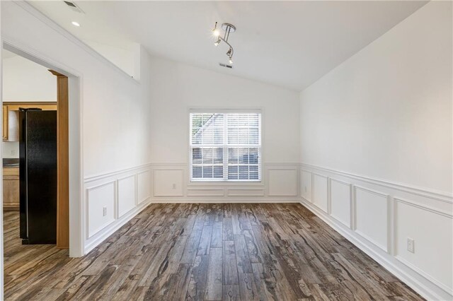 unfurnished dining area featuring vaulted ceiling and dark wood-type flooring