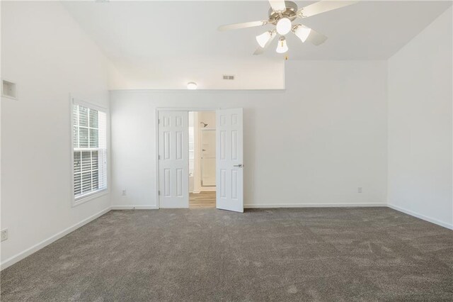 unfurnished room featuring ceiling fan, lofted ceiling, and dark colored carpet