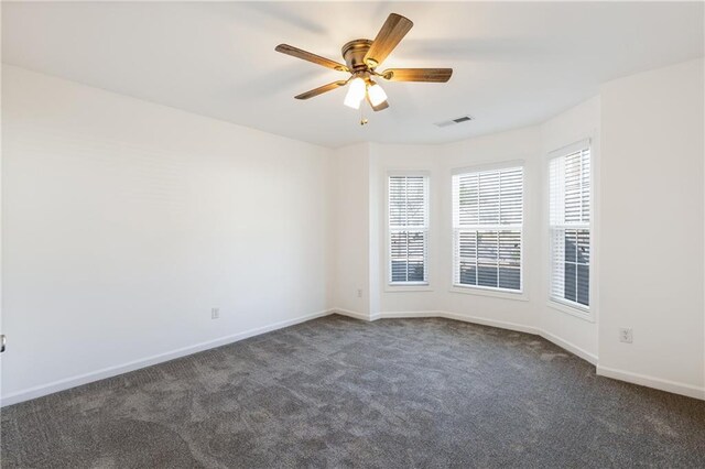 empty room with dark colored carpet and ceiling fan