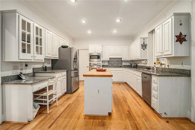 80 Stratford Pl NE, Atlanta, GA 30342 - kitchen with appliances with stainless steel finishes, a kitchen island, white cabinetry, ornamental molding, and light wood-style floors