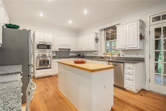 80 Stratford Pl NE, Atlanta, GA 30342 - kitchen featuring appliances with stainless steel finishes, butcher block countertops, ornamental molding, a kitchen island, and white cabinetry