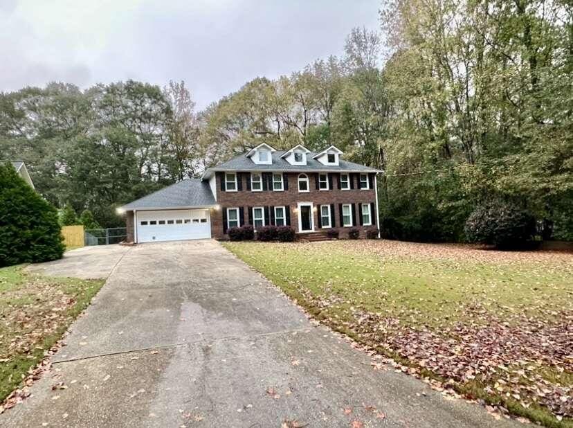 colonial house featuring a garage and a front lawn