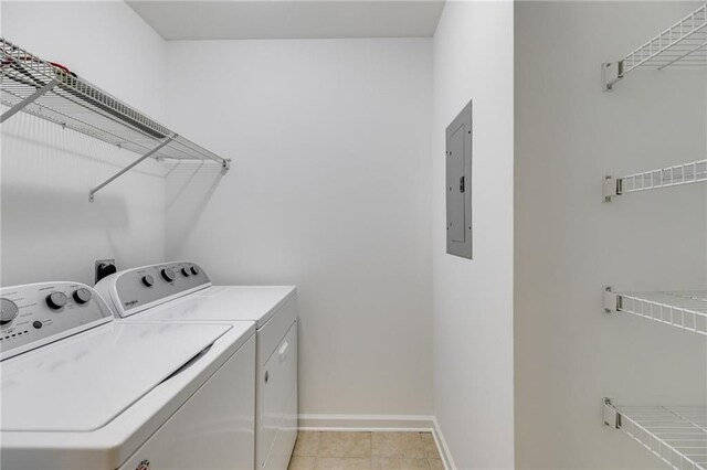 laundry room featuring light tile patterned floors, electric panel, and washing machine and clothes dryer