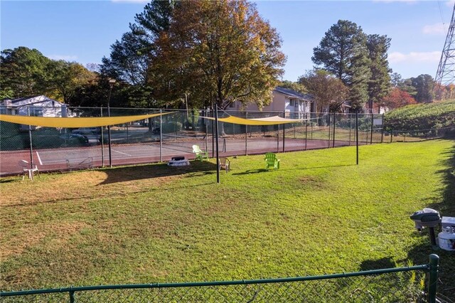 view of property's community featuring a lawn and tennis court