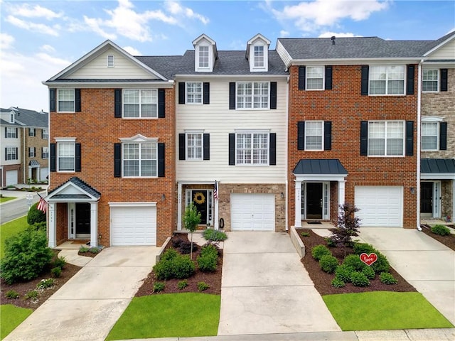 townhome / multi-family property with brick siding, driveway, and a garage