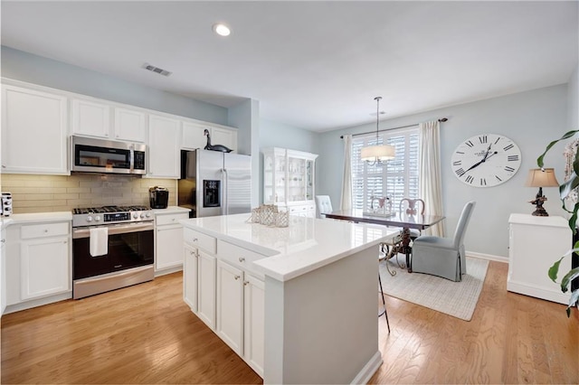 kitchen featuring visible vents, decorative backsplash, white cabinetry, and stainless steel appliances