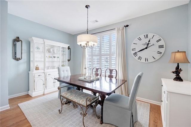 dining area featuring baseboards, an inviting chandelier, visible vents, and light wood-type flooring