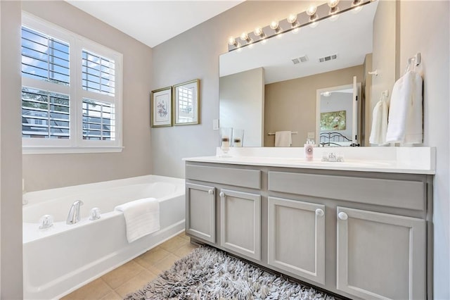 bathroom with double vanity, tile patterned flooring, a garden tub, and visible vents