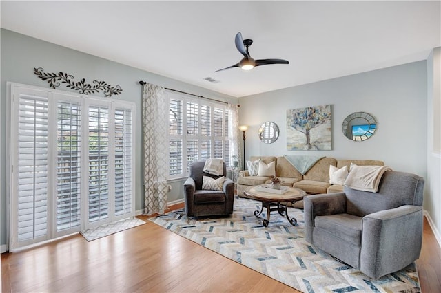 living room with a ceiling fan, baseboards, visible vents, and wood finished floors