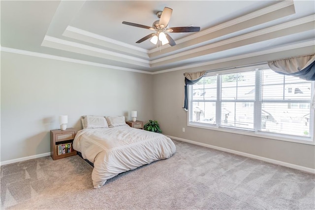 carpeted bedroom featuring baseboards, a ceiling fan, a tray ceiling, and ornamental molding