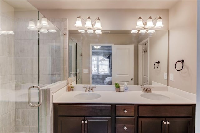 full bathroom featuring double vanity, a shower stall, ensuite bathroom, and a sink