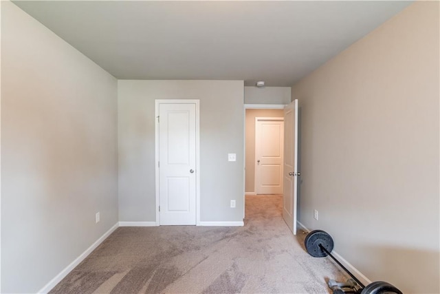 unfurnished bedroom featuring light carpet and baseboards