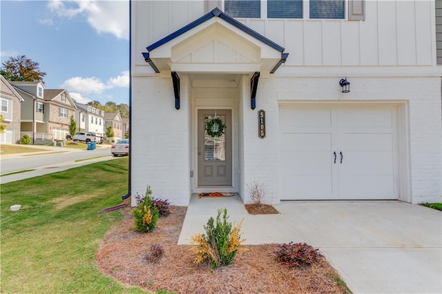 doorway to property with a lawn, driveway, a residential view, board and batten siding, and brick siding