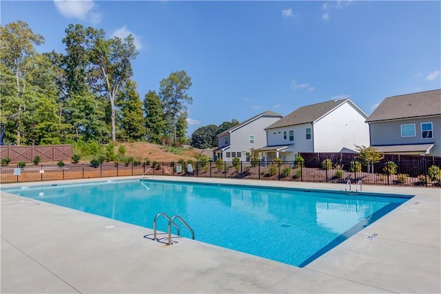 community pool with a patio, fence, and a residential view