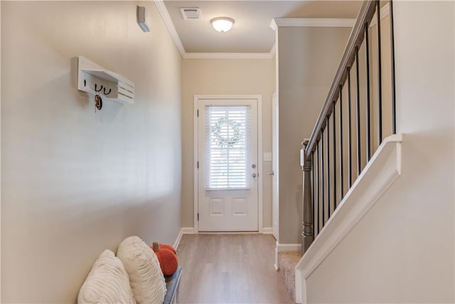 doorway to outside with visible vents, crown molding, baseboards, stairway, and light wood-style floors