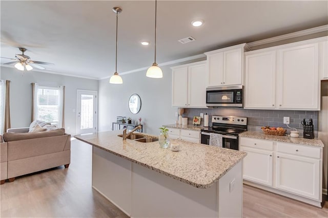 kitchen with light wood-style flooring, a sink, decorative backsplash, stainless steel appliances, and open floor plan