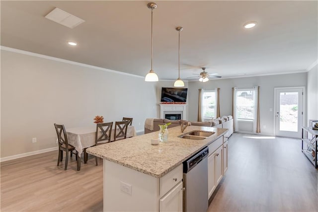 kitchen featuring a glass covered fireplace, ornamental molding, a sink, light wood-style floors, and dishwasher