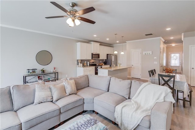 living room with light wood-type flooring, a ceiling fan, recessed lighting, crown molding, and baseboards