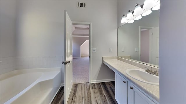 full bathroom featuring vanity, wood finished floors, visible vents, baseboards, and a bath