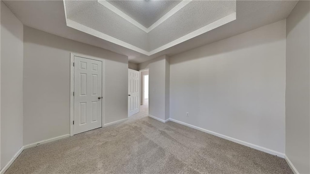 carpeted spare room with baseboards, a textured ceiling, and a tray ceiling