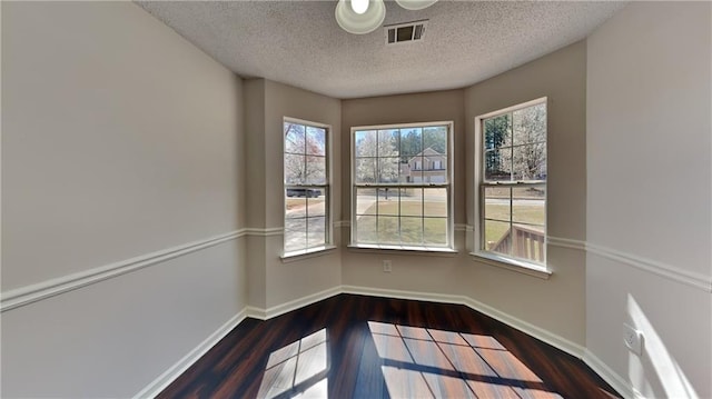 unfurnished dining area featuring visible vents, baseboards, and wood finished floors