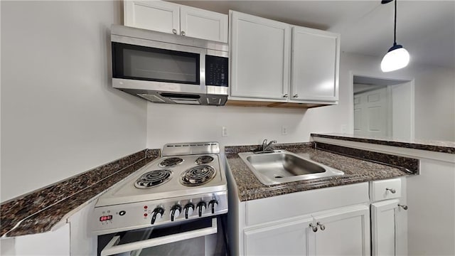 kitchen with electric range, a sink, white cabinets, stainless steel microwave, and decorative light fixtures