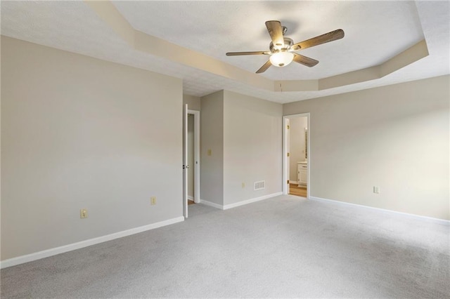 carpeted empty room featuring a raised ceiling and ceiling fan