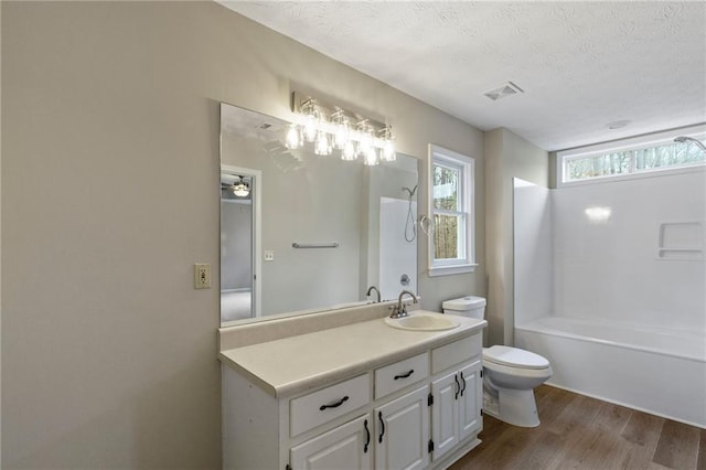 full bathroom with wood-type flooring, vanity, a textured ceiling, and toilet