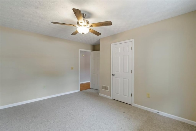 unfurnished bedroom featuring ceiling fan, light carpet, and a textured ceiling