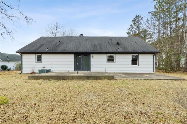 rear view of property with central AC unit, a lawn, and a patio