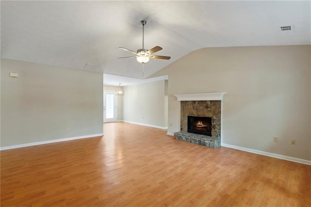 unfurnished living room with ceiling fan, lofted ceiling, a stone fireplace, and light hardwood / wood-style flooring