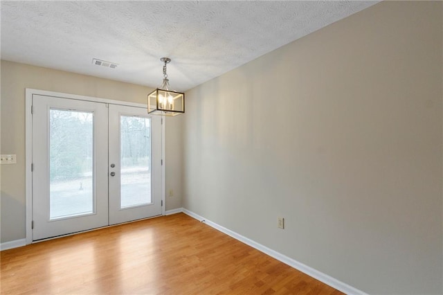 entryway featuring wood-type flooring, a notable chandelier, a textured ceiling, and french doors