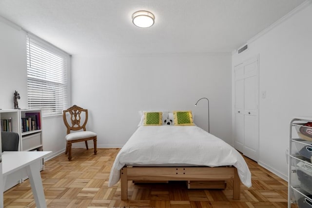 bedroom with a closet, ornamental molding, and light parquet floors