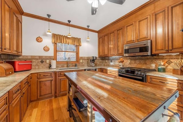 kitchen with gas range oven, ornamental molding, sink, and wood counters