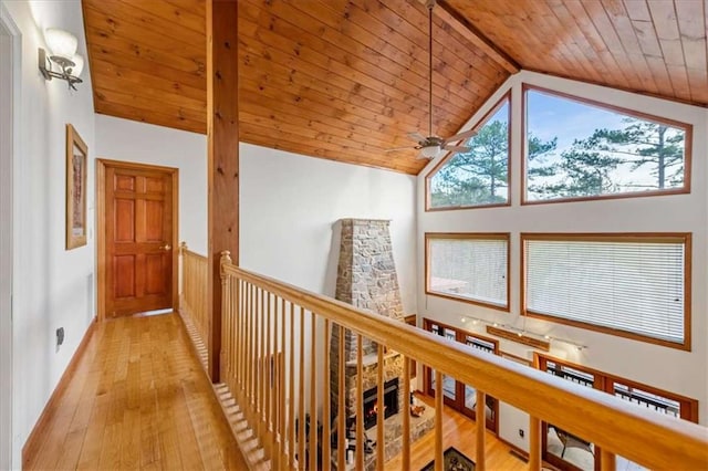 hall with high vaulted ceiling, light wood-type flooring, and wood ceiling