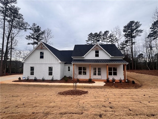 modern inspired farmhouse with metal roof, a standing seam roof, a porch, board and batten siding, and brick siding