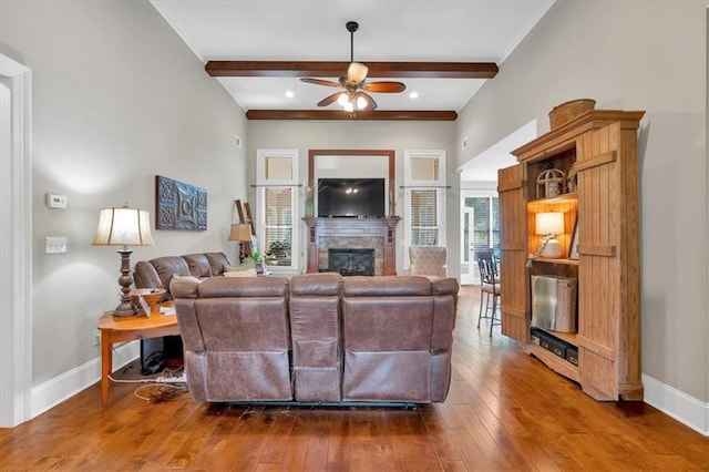 living room with ceiling fan, hardwood / wood-style floors, a fireplace, and beam ceiling