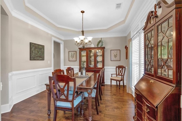 dining area with an inviting chandelier, a tray ceiling, dark hardwood / wood-style floors, and crown molding