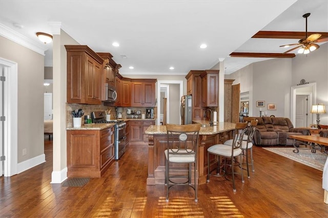 kitchen featuring appliances with stainless steel finishes, a kitchen bar, decorative backsplash, light stone counters, and kitchen peninsula