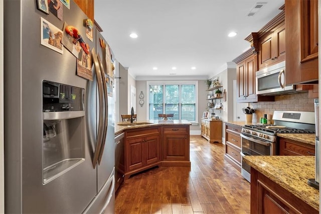 kitchen featuring sink, dark wood-type flooring, appliances with stainless steel finishes, backsplash, and light stone countertops