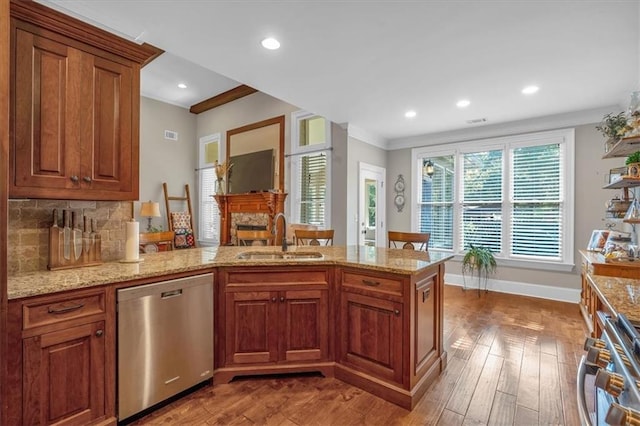 kitchen featuring a fireplace, dishwasher, sink, decorative backsplash, and light stone counters