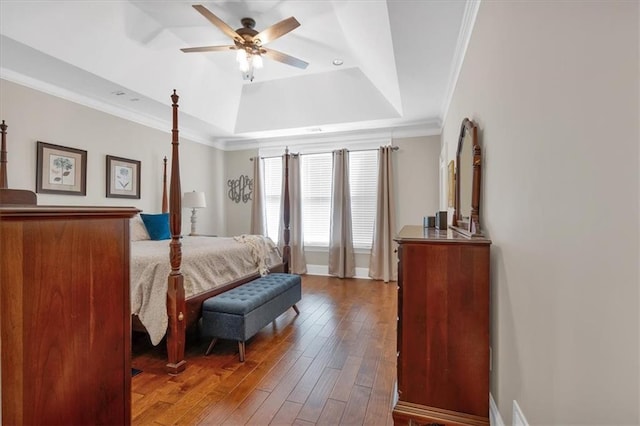 bedroom featuring ceiling fan, ornamental molding, wood-type flooring, and a raised ceiling