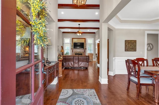 entrance foyer with dark wood-type flooring, ceiling fan, ornamental molding, and beam ceiling