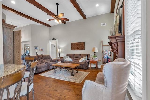 living room with dark wood-type flooring, ceiling fan, and beamed ceiling