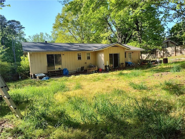 back of house featuring roof with shingles and board and batten siding