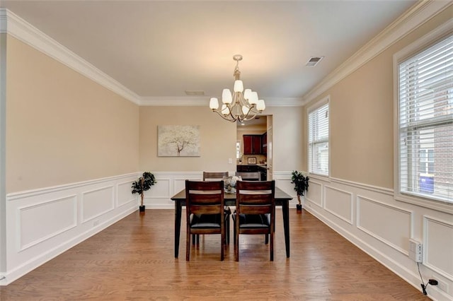 dining area with ornamental molding, hardwood / wood-style floors, and a notable chandelier