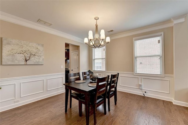 dining space with dark hardwood / wood-style flooring, ornamental molding, and a chandelier